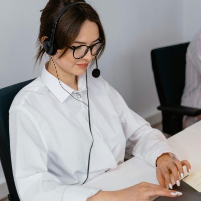 Cheerful woman in a call center using a laptop and headset for customer support.