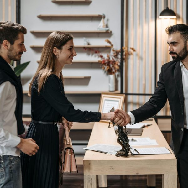 A professional meeting in a modern office with a couple shaking hands with a businessman.