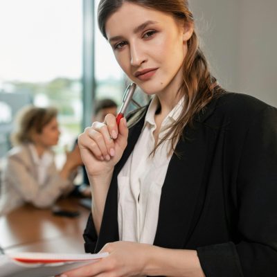 Professional woman in office attire holding documents, leading a meeting.