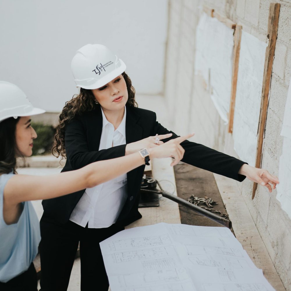 Two female architects discussing building plans outdoors, emphasizing teamwork and women leadership.